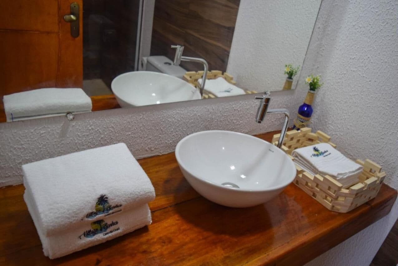 A bathroom with a white sink, a mirror, and a wooden vanity. There are towels and toiletries on the vanity.