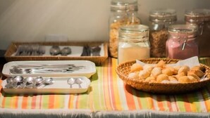 Pöytä, jonka päällä on raidallinen pöytäliina, kori täynnä leipää ja purkkeja erilaisia mausteita.