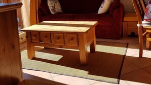 Uma sala de estar aconchegante com uma mesa de centro de madeira, um sofá vermelho e uma cadeira de madeira.