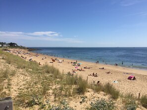 Une plage où l’on peut se prélasser au soleil et se baigner, un ciel dégagé et une mer calme.