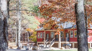 A lodge with a red exterior, a porch with outdoor seating, and a view of the surrounding forest. - Bear Necessities (Vesuvius)