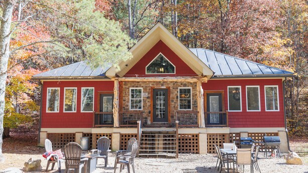 A red cabin with a stone facade, large windows, and a front porch with outdoor seating. - Bear Necessities (Vesuvius)