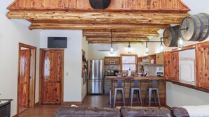 A rustic kitchen with wooden beams, a stainless steel refrigerator, and a bar area with stools. - Bear Necessities (Vesuvius)