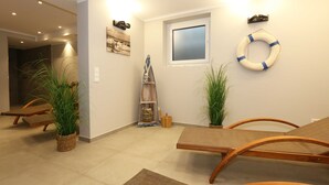 Una habitación con una mesa y sillas de madera, una escalera, un flotador en la pared y plantas en macetas.