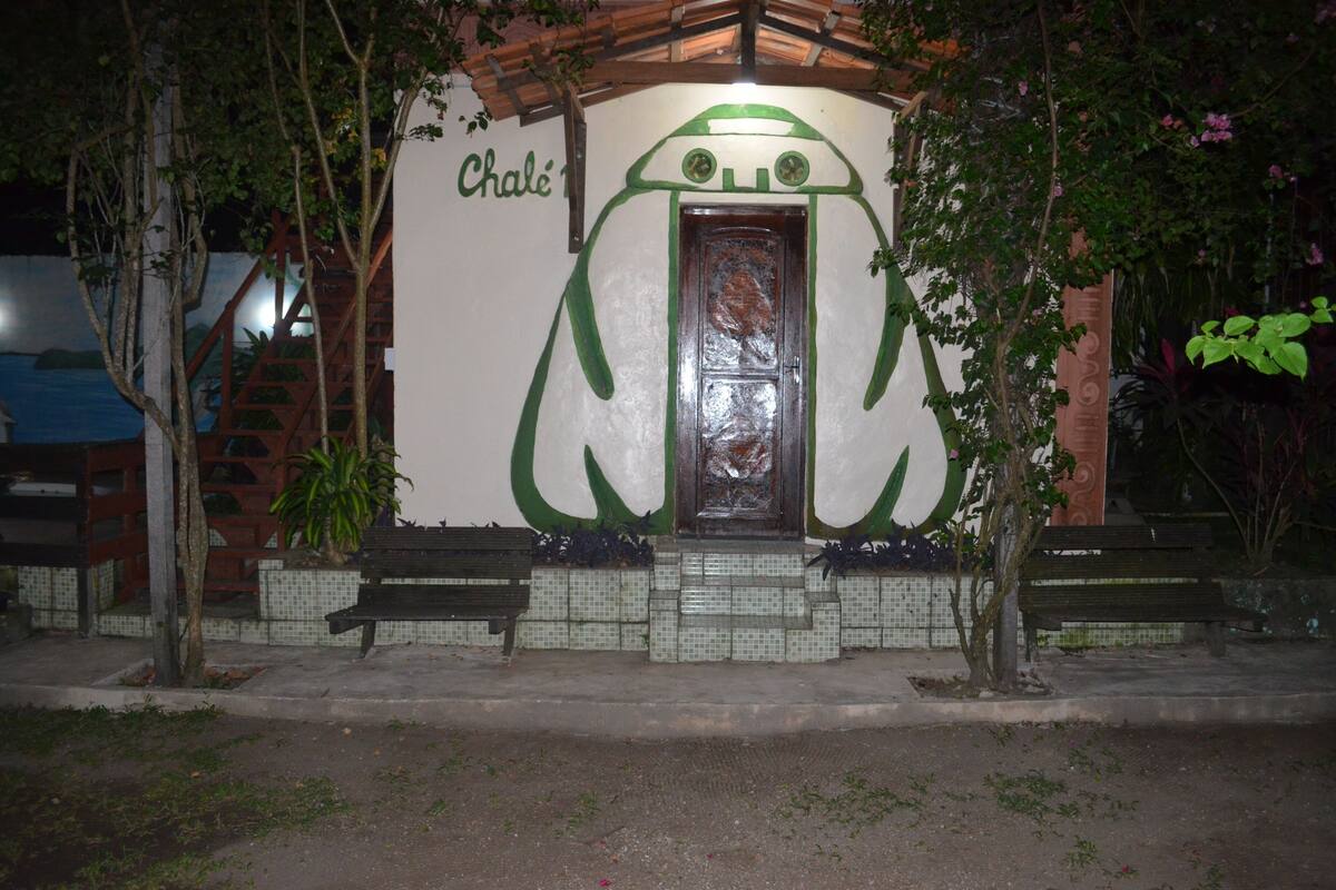 Um edifício com uma entrada em formato de sapo, escadaria de madeira e parede revestida de azulejos.