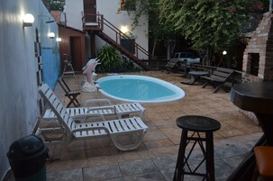 Una piscina al aire libre, sillones reclinables de piscina