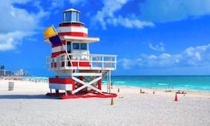 Une tour de surveillance avec un drapeau, une plage et l’océan.