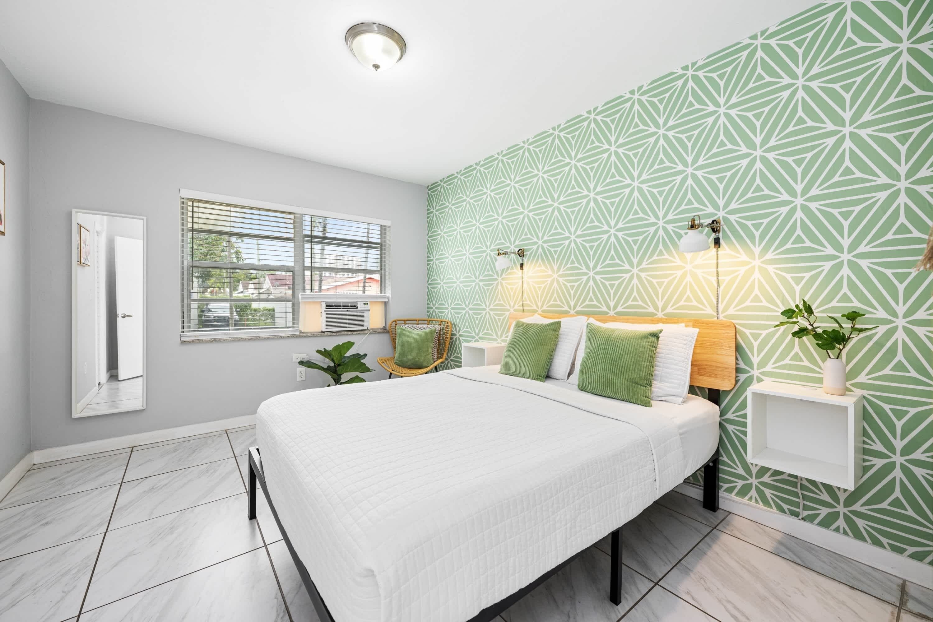 Un dormitorio con cama, ventana, luz empotrada y una planta.