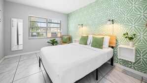 A bedroom with a bed, a window, a wall-mounted light, and a plant. - HAVANA5 | spacious escape in miami's cultural hub (Miami)