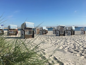 Beach huts with striped awnings, a sandy beach, and a pier in the background. - Vacationer village 27c, Germany (Ostseebad Boltenhagen)
