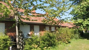 A row of brick houses with red-tiled roofs, surrounded by greenery and a grassy lawn. - Vacationer village 27c, Germany (Ostseebad Boltenhagen)