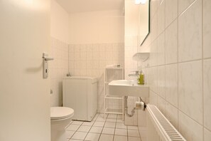 A small, white bathroom with a toilet, sink, and radiator. - Vacationer village 27c, Germany (Ostseebad Boltenhagen)
