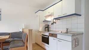 A compact kitchen with white cabinets, a built-in oven, and a coffee maker. - Vacationer village 27c, Germany (Ostseebad Boltenhagen)