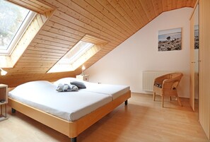 A bedroom with a wooden ceiling, a bed, a chair, and a picture on the wall. - Vacationer village 27c, Germany (Ostseebad Boltenhagen)