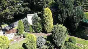 Un jardin aménagé avec différents arbres et arbustes, un mur de pierre et une clôture en bois.