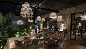 An indoor dining area with multiple wooden tables and chairs, surrounded by lush greenery. - Las Brisas Merida (Mérida)
