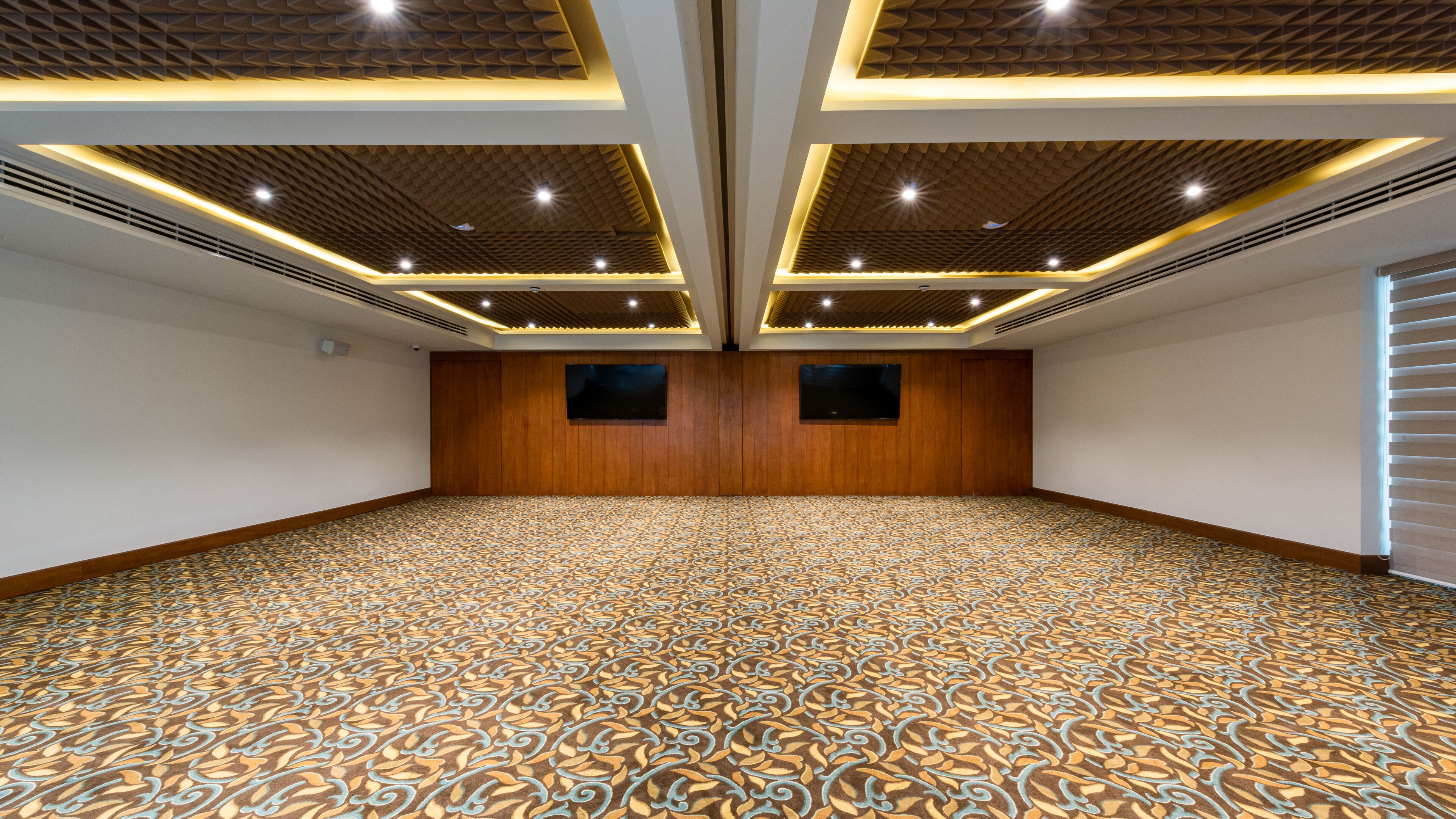 A conference room with a patterned carpet, wooden panel walls, and recessed lighting.