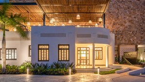 A modern building with a covered entrance, large windows, and a stone wall. - Las Brisas Merida (Mérida)