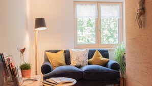 A living room with a sofa, a lamp, a window, and a wall-mounted sculpture. - Vacation apartment Gutgehen (1-2 persons) - Moosbrugger Rosmarie - Haus WohlSEIN (Schoppernau)