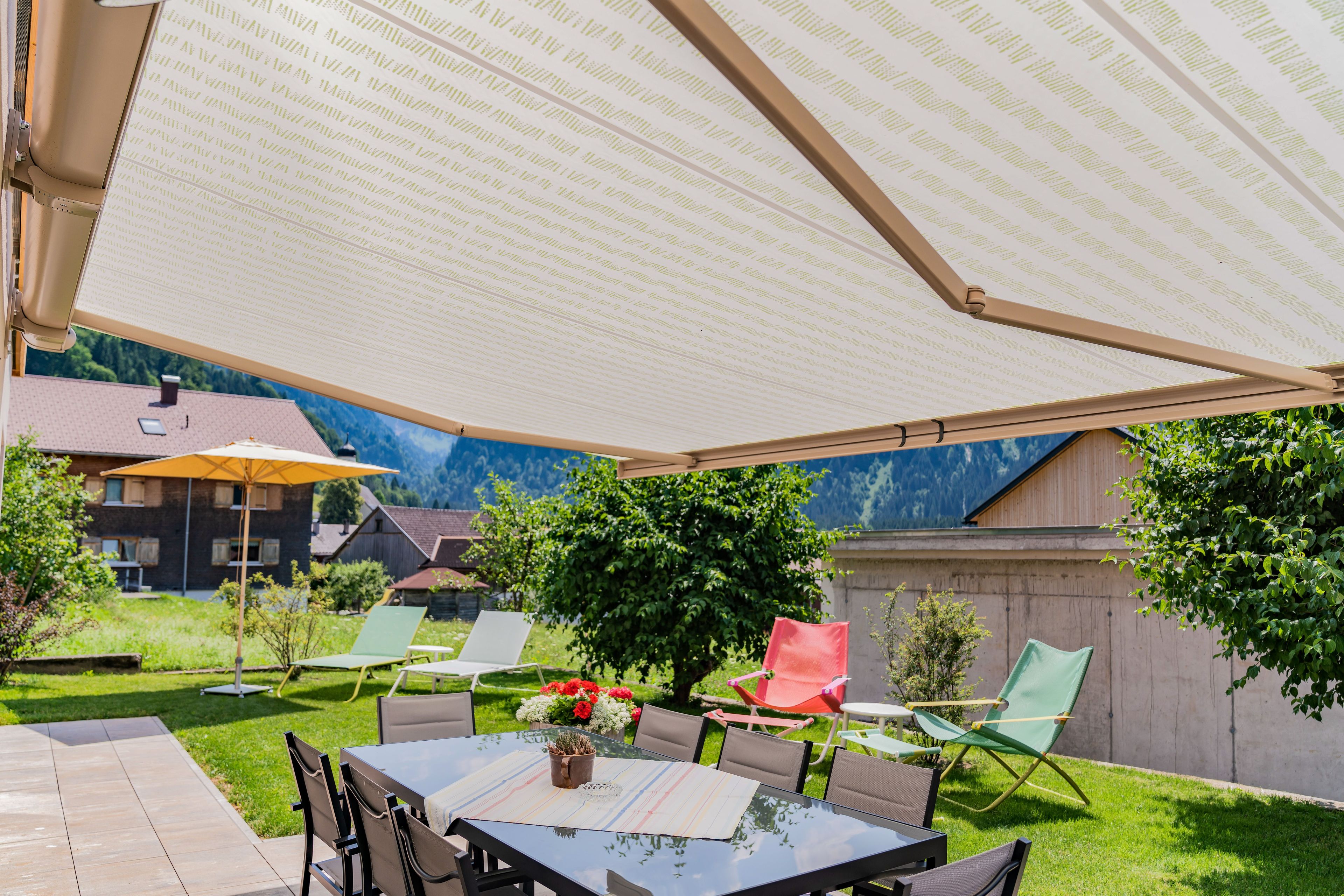 An outdoor patio with a table, chairs, and a large umbrella.