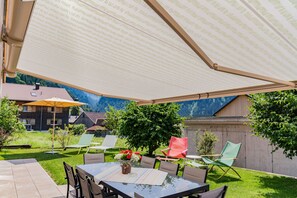 An outdoor patio with a table, chairs, and a large umbrella.