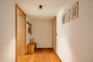 A hallway with wooden flooring, a bench, a coat rack, and framed pictures on the wall.