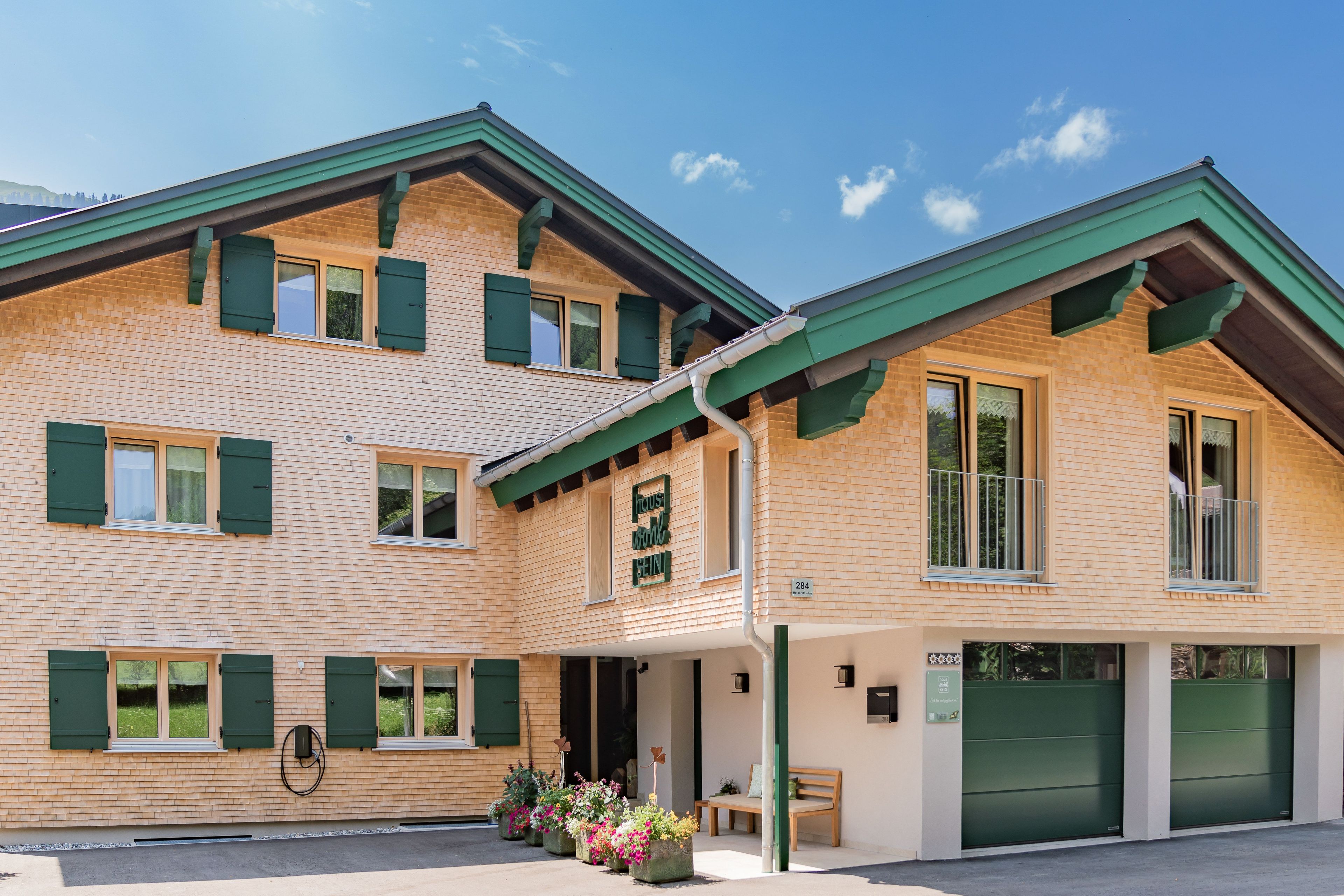 A two-story building with a brick facade, green shutters, and a green awning.