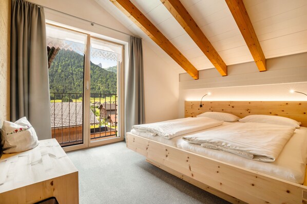 Ein Zimmer mit einem Holzbett, einem Schreibtisch und Blick auf einen Berg durch eine Schiebetür.