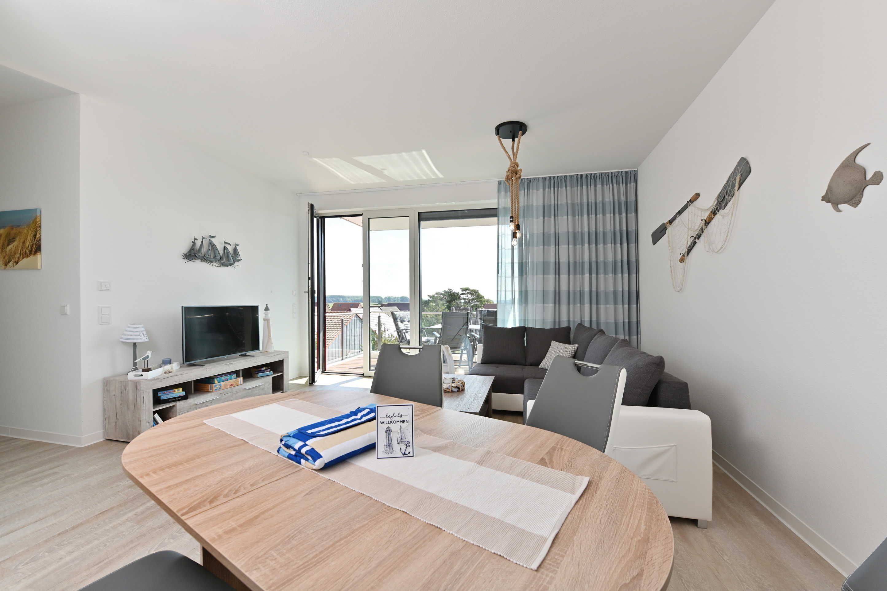 Ein modernes Wohnzimmer mit einem Holzespeisetisch, einer grauen Couch und einem Fernseher auf einem Holzbodenständer.