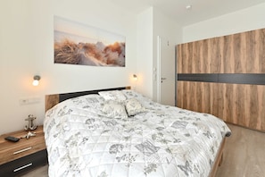 Une chambre à coucher comprenant un lit, une table de chevet, un tableau accroché au mur et une armoire.