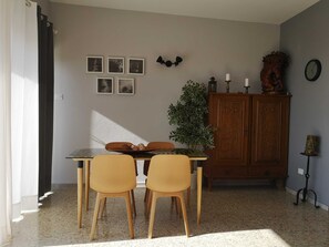 A dining area with a table, two chairs, a cabinet, and wall-mounted decor.