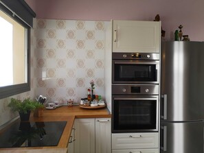 A kitchen with a built-in oven, a refrigerator, and a window.