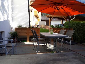 An outdoor patio with a table, chairs, and a large umbrella.
