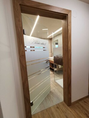 A hallway with a wooden frame door leading to a room with a bed and a bathroom.