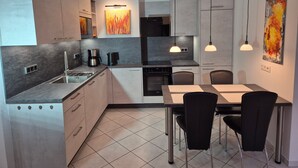 Una cocina moderna con gabinetes grises, encimera negra y un comedor con mesa y sillas.