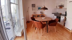 Una cocina moderna con armarios blancos, una mesa de comedor con seis sillas y una lámpara colgante.