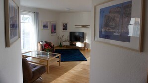 Una sala de estar moderna con un televisor de pantalla plana, un sofá, una mesa de centro y una alfombra azul.