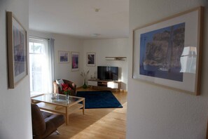 Un salon moderne avec un téléviseur à écran plat, un canapé, une table basse et un tapis bleu.