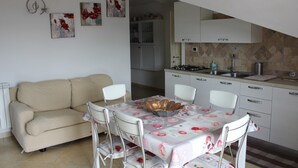 A compact living space with a dining area, kitchenette, and a sofa. - IL GABBIANO (IUN: P5444) (San Giovanni Suergiu)