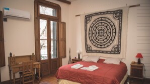 A bedroom with a large bed, a wooden desk, a chair, a tapestry, and a window with shutters. - La Casa de Bulnes (Buenos Aires)