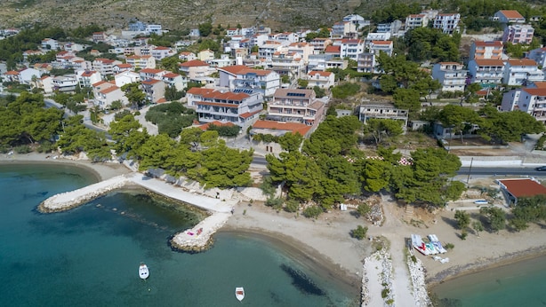 Vue aérienne d’une ville côtière avec des immeubles résidentiels, une plage et une jetée.