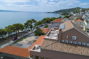 A coastal building with a tiled roof, multiple air conditioning units, and a view of the sea. - Pansion Dalmacija (Dugi Rat)