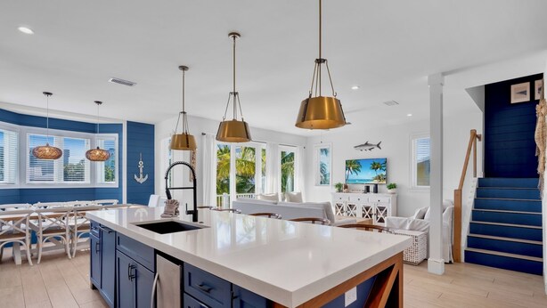 A modern kitchen with a large island, pendant lighting, and a view of the outdoors. - Luxury Beach Retreat:  Rooftop Views, Pool and Spa (Bradenton Beach)