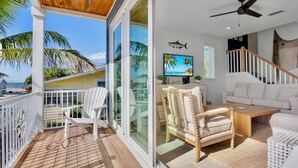 A spacious balcony with a wooden ceiling, white outdoor furniture, and a view of the ocean. - Luxury Beach Retreat:  Rooftop Views, Pool and Spa (Bradenton Beach)