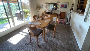 Ein Essbereich mit einem Holztisch, Stühlen und einer Chandelier. Eine Schiebeglastür führt zu einem Garten.