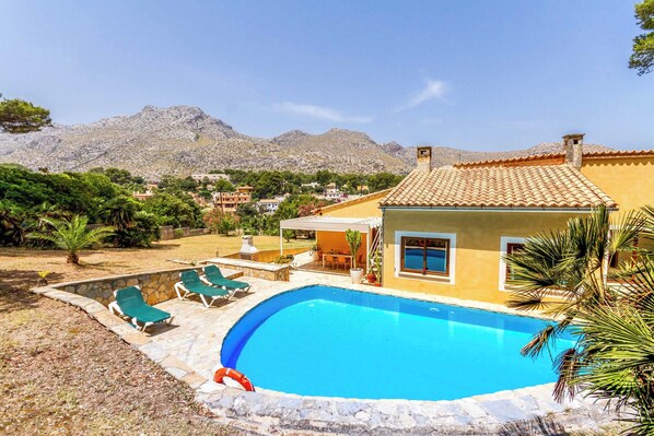 A swimming pool with lounge chairs, a patio area, and a mountain backdrop.