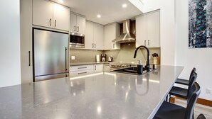 A modern kitchen with a stainless steel refrigerator, a microwave, a stove, and a sink.