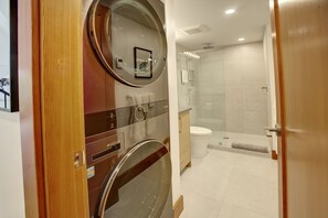 Moderni kylpyhuone, jossa on lasinen suihkuseinä, wc ja pesukone.