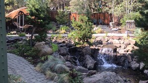 Un giardino con una piccola cascata, rocce e un vialetto lastricato.