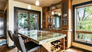 Una cucina moderna con una grande isola, mobili in legno e ampie finestre che si affacciano sul verde.